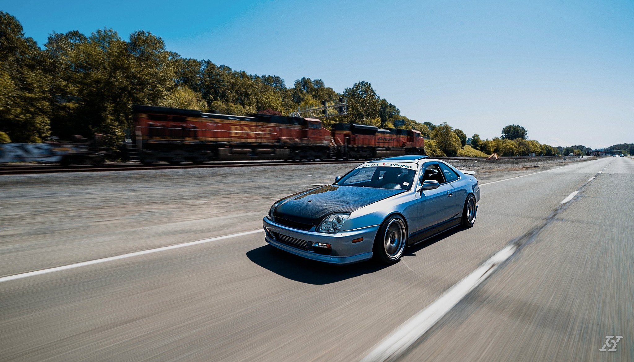 Crystal Blue Metallic Honda Prelude driving alongside a BNSF freight train after an exterior detail by High Standard Auto Salon